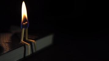Two burning matches in the form of people sit on a book in the dark. The concept of love. video