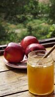 Apples red whole and sliced with a jar of honey on the traditional Jewish holiday of Rosh Hashana on a wooden table by the window on a sunny day. Close-up, vertical video