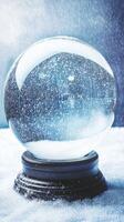Snow globe resting on a snow covered surface with snow falling in the background photo