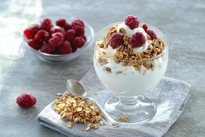 Yogurt decorated with raspberries and crunchy granola for a healthy breakfast photo