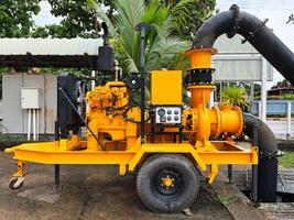 large mobile industrial water pump system used for irrigation, flood control, industrial processes, machinery, mounted on a wheeled platform, features a robust design with yellow, high functionality photo