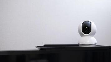 Selective focus of Smart home wireless security camera set up on white table at home, using for security monitoring or private cctv photo