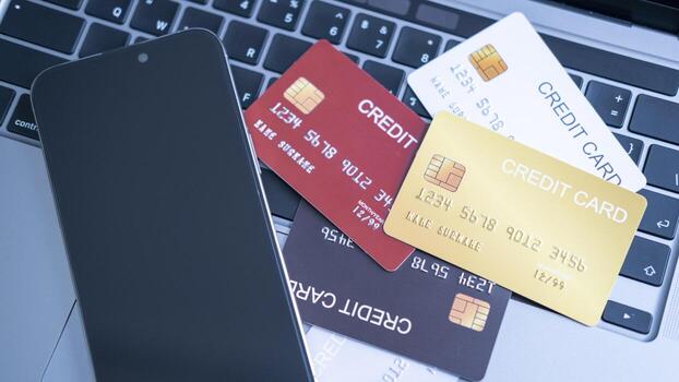 A collection of credit cards in different colors, on a laptop keyboard next to a smartphone. the concept of multiple payment options, digital banking, and secure online transactions in the financial. photo