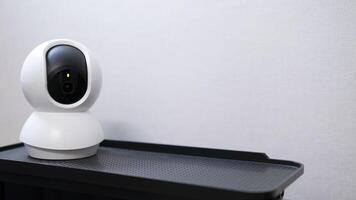 Selective focus of Smart home wireless security camera set up on white table at home, using for security monitoring or private cctv photo