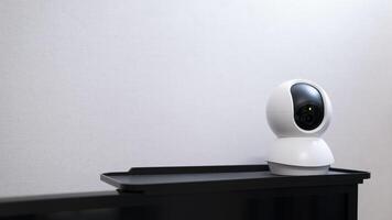 Selective focus of Smart home wireless security camera set up on white table at home, using for security monitoring or private cctv photo