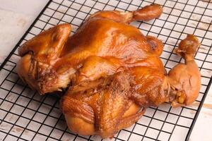 Ayam Panggang. Whole roasted chicken with soy sauce and spices. on the cooling rack. Indonesian food. photo