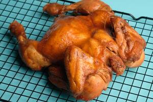 Ayam Panggang. Whole roasted chicken with soy sauce and spices. on the cooling rack. Indonesian food. photo