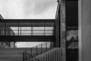 black and white photo of a building with a glass walkway and stairs