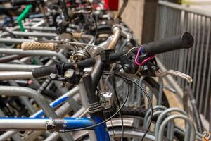 Old bicycle with worn handlebars parked in a row with other bikes photo