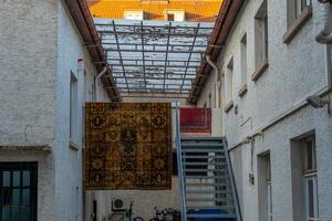large rug hangs from the ceiling in a narrow hallway photo