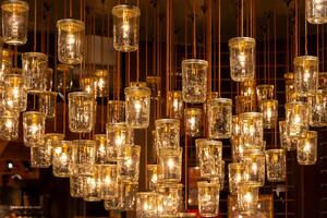 cluster of mason jars hanging from the ceiling with lights inside photo