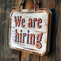 creative job poster with a wooden sign on a chain and the text We are hiring on the background of a wooden door photo
