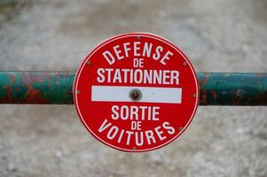 In the image, there is a weathered gate with a red sign in French indicating no parking photo