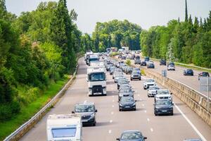 The highway is experiencing heavy traffic, set against a backdrop of lush greenery photo