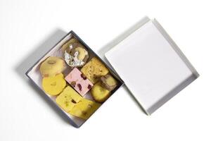 Various Indian mixed sweets made of milk and pulses during festivals in cardboard box on white surface. photo