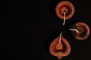 Top view of Diwali oil lamps on black background with space for text. photo