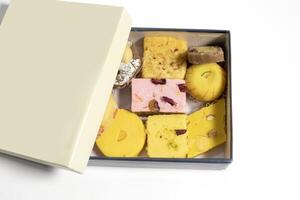 Indian mixed sweets made of milk and pulses during festivals in cardboard box on white surface. photo