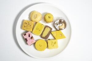 Various traditional Indian sweets made of milk and pulses during a festive event on a plate on a white surface during festivals. Top view photo