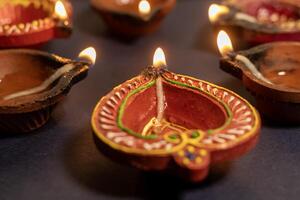 Beautiful diya lights lit during Diwali celebration on black background. photo