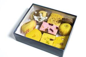 Traditional various Indian mixed sweets made of milk in cardboard box on white surface. photo