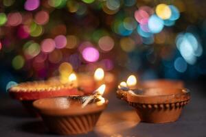 Close up of Diwali diya or lighting lamp over colorful bokeh background. photo