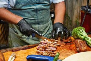 A chef using a torch to caramelize and flavor grilled meat on a wooden board, creating a savory and smoky finish. photo