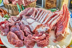 A variety of raw meat cuts, including ribs and tenderloin, displayed on a wooden board, ready for preparation and cooking photo
