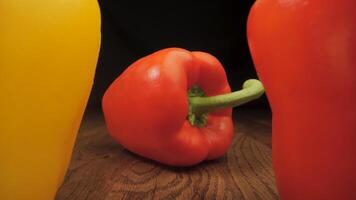Red and yellow peppers on a wooden surface. The camera moves between the vegetables. Cooking concept. video