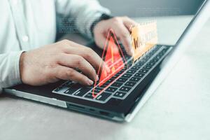 Businessman programmer, developer using laptop computer with triangle caution warning sign. photo
