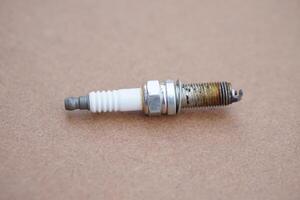 Spark plug on brown background. spare part of car engine. Concept, machine maintenance, fix, repair, check or diagnose automobile problems by engine specialist. photo