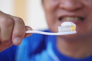Close up man holds toothbrush with toothpaste. Concept, dental health care. Brush teeth with fluoride toothpaste for hygiene, clean and strong teeth. Prevention from tooth decay. photo