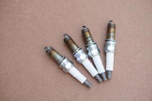 Spark plugs on brown background. spare part of car engine. Concept, machine maintenance, fix, repair, check or diagnose automobile problems by engine specialist. photo
