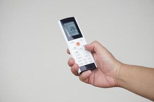Close up hand hold remote control of air conditioner. Concept, electronics equipment, a remote control can be used to operate devices or appliances with variety functions. Adjust temperature mode. photo