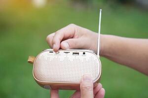 Hands hold portable mini radio. Concept, audio electronics for listening to music, songs or news from radio wave channel station. Analog amplifier for relaxation and lifestyle. photo