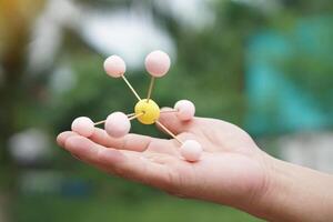 Closeup hand hold DIY molecule structure made from toothpicks and plasticine for teaching. Concept, teaching aids, educational materials. science lesson about molecule. Creative task from learning. photo