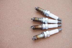 Spark plugs on brown background. spare part of car engine. Concept, machine maintenance, fix, repair, check or diagnose automobile problems by engine specialist. photo