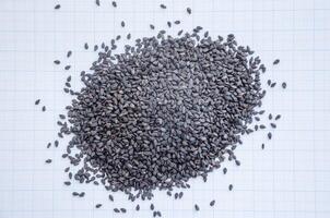 black sesame seeds in a heap on a background of graph paper photo