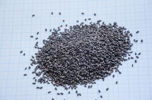 black sesame seeds in a heap on a background of graph paper photo