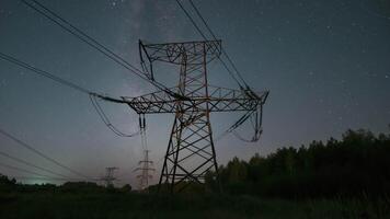 Nighttime view of high voltage power lines against the backdrop of moving stars in the night sky on a moonlit night. Concept of electricity and energy generation video
