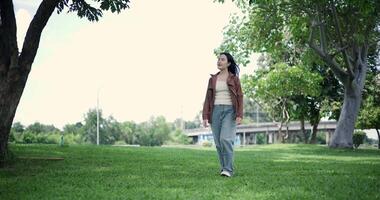 Handheld low angle view shot, Happy young woman enjoys a relaxing walk in a park, Enjoying the fresh air and the beauty of nature around her. video