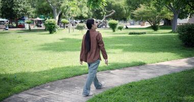 Handheld shot, Relaxed woman is enjoying a leisurely stroll and looking around a park filled with fresh air and soft sunlight. Enjoy a happy holiday video
