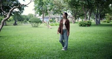 Handheld shot, Relaxed woman is enjoying a leisurely stroll and looking around a park filled with fresh air and soft sunlight. Enjoy a happy holiday video