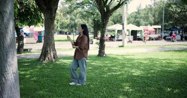 Footage handheld shot, Happy young woman enjoys a relaxing walk in a park, Enjoying the fresh air and the beauty of nature around her. video