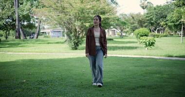 Handheld shot, Relaxed woman is enjoying a leisurely stroll and looking around a park filled with fresh air and soft sunlight. Enjoy a happy holiday video