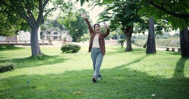 Handheld shot, Happy woman enjoys takes a photo on mobile phone while walking in a park. A holiday time surrounded by nature video