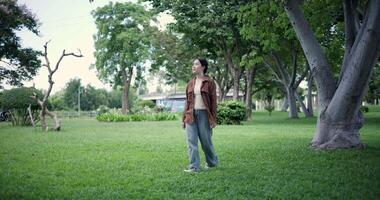 Handheld shot, Relaxed woman is enjoying a leisurely stroll and looking around a park filled with fresh air and soft sunlight. Enjoy a happy holiday video