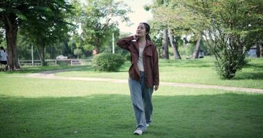Handheld shot, Relaxed woman is enjoying a leisurely stroll and looking around a park filled with fresh air and soft sunlight. Enjoy a happy holiday video