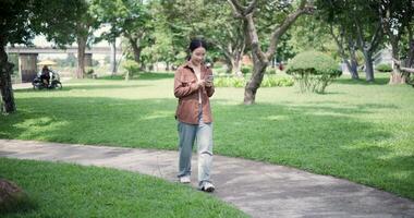 Handheld shot, Happy woman enjoys takes a photo on mobile phone while walking in a park. A holiday time surrounded by nature video