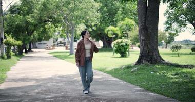 Handheld shot, Relaxed woman is enjoying a leisurely stroll and looking around a park filled with fresh air and soft sunlight. Enjoy a happy holiday video