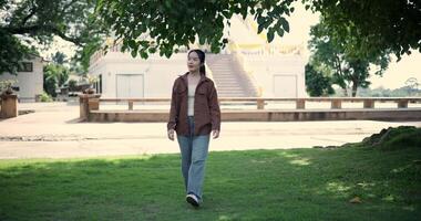 Handheld shot, Relaxed woman is enjoying a leisurely stroll and looking around a park filled with fresh air and soft sunlight. Enjoy a happy holiday video